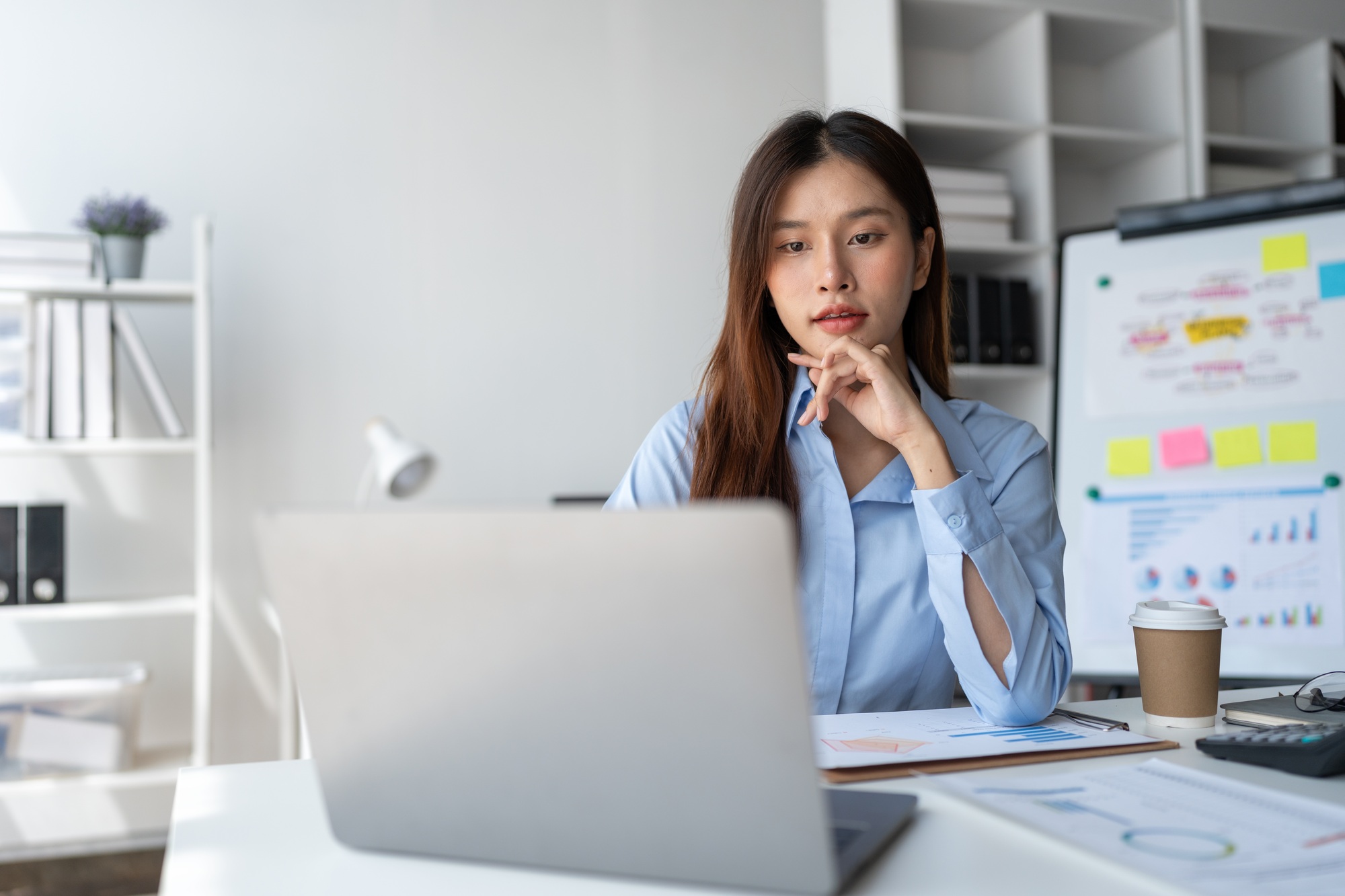 Asian businesswoman sitting and thinking analyze financial reports Business growth using laptop comp