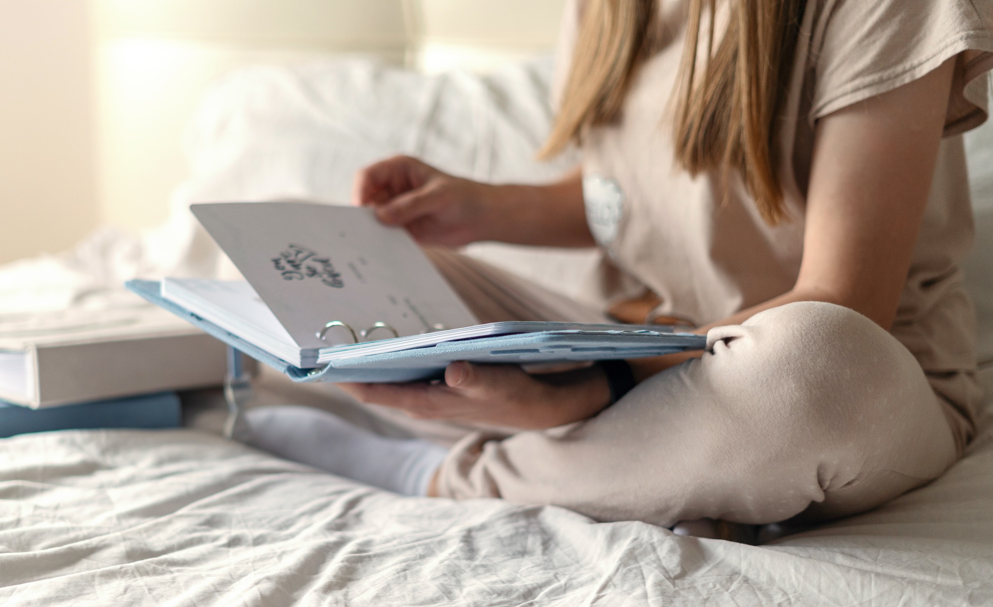 Cropped woman hands holding and watching a family photo album. Mother sit on bed and watching album