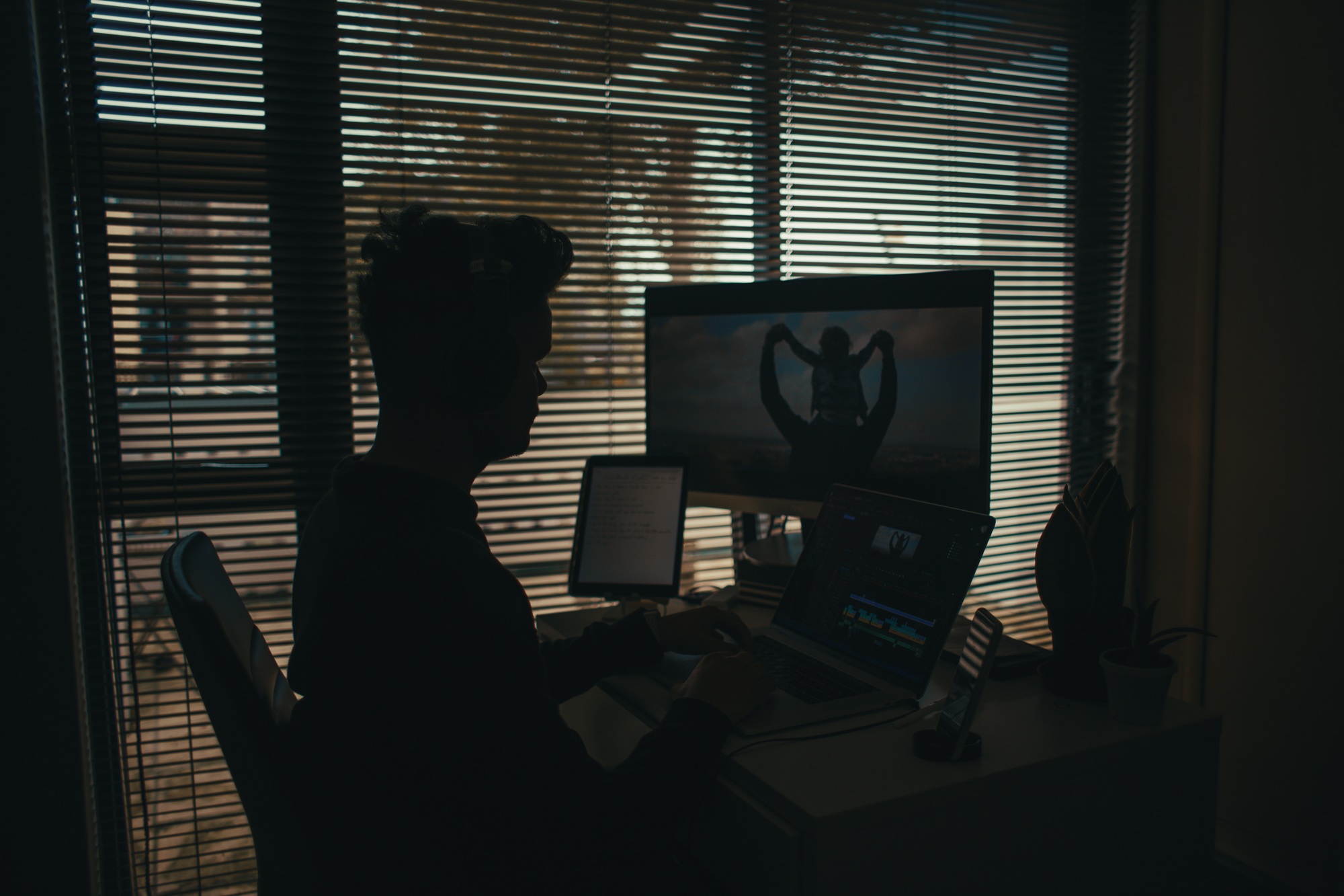 Male Filmmaker editing video in dark room